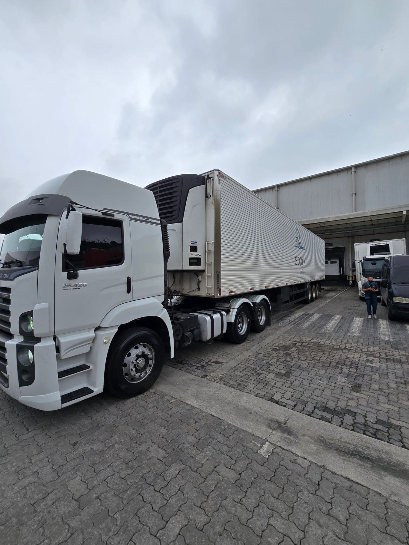 Cavalo mecânico branco com baú refrigerado da Stork estacionado na doca